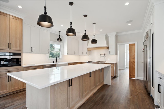 kitchen with hanging light fixtures, dark wood-type flooring, premium range hood, crown molding, and a spacious island