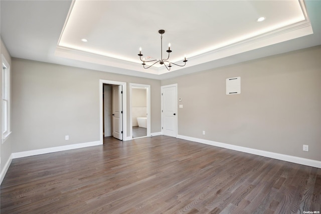 unfurnished bedroom with a raised ceiling, connected bathroom, dark hardwood / wood-style flooring, and an inviting chandelier