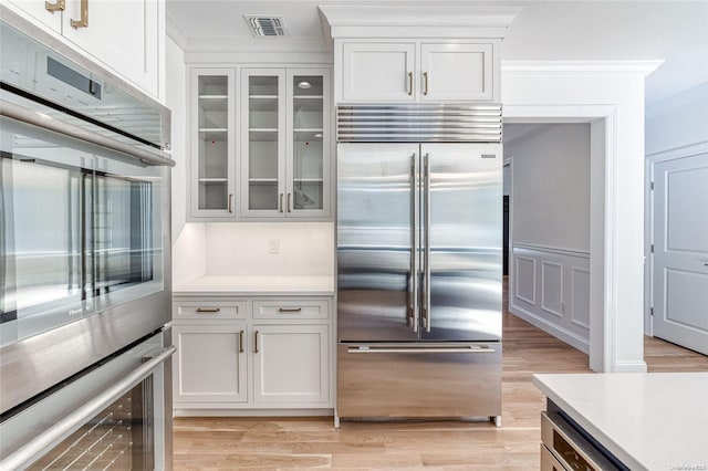 80 Ocean Ave, Massapequa, NY 11758 - kitchen with visible vents, crown molding, glass insert cabinets, appliances with stainless steel finishes, and white cabinetry