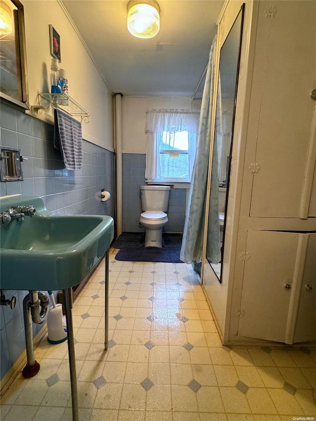 bathroom with a shower with curtain, sink, crown molding, toilet, and tile walls