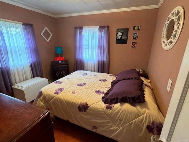 bedroom with hardwood / wood-style flooring, ornamental molding, and multiple windows