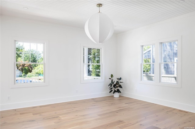 spare room featuring crown molding, a wealth of natural light, and light hardwood / wood-style flooring