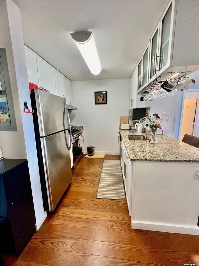 kitchen featuring light wood-type flooring, white cabinetry, light stone counters, and appliances with stainless steel finishes