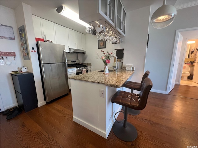 kitchen with white cabinets, sink, appliances with stainless steel finishes, dark hardwood / wood-style flooring, and kitchen peninsula