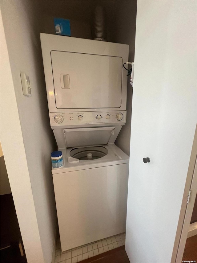 laundry area with tile patterned flooring and stacked washer and clothes dryer