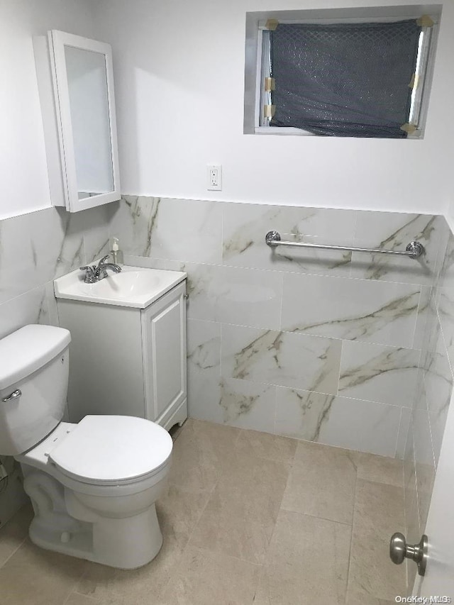 bathroom featuring tile patterned flooring, vanity, tile walls, and toilet