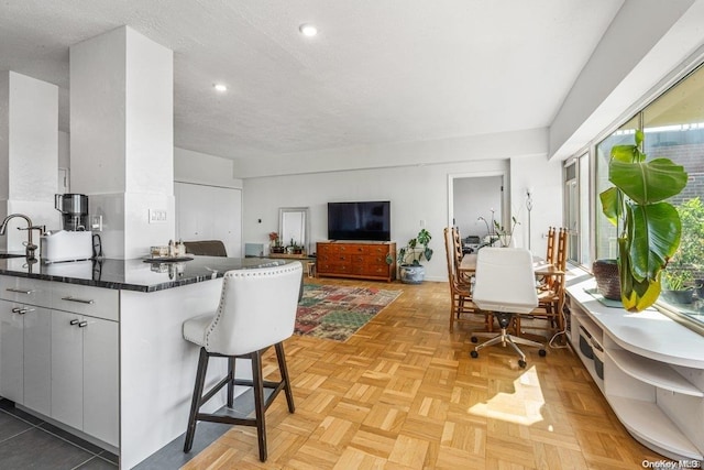 166-25 Powells Cove Blvd Unit 21G, Beechhurst, NY 11357 - kitchen with healthy amount of natural light, a kitchen bar, recessed lighting, a sink, and dark stone counters