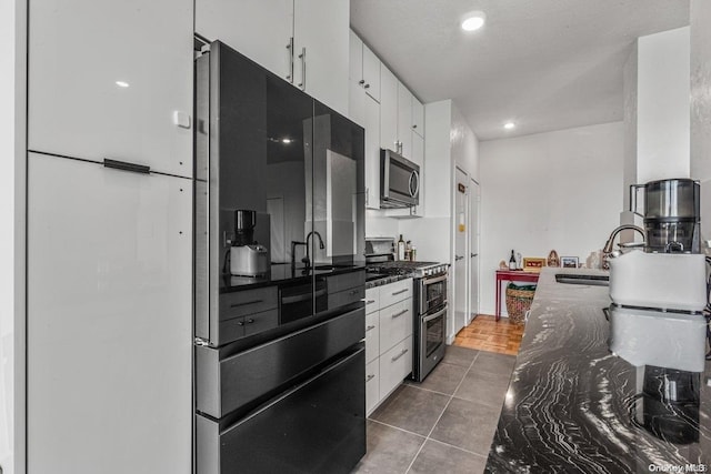 166-25 Powells Cove Blvd Unit 21G, Beechhurst, NY 11357 - kitchen featuring stainless steel appliances, white cabinetry, a sink, dark stone countertops, and recessed lighting