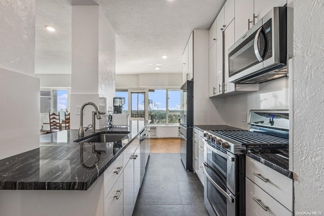 166-25 Powells Cove Blvd Unit 21G, Beechhurst, NY 11357 - kitchen featuring stainless steel appliances, a sink, a textured ceiling, white cabinets, and dark tile patterned floors