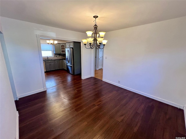 unfurnished dining area featuring dark hardwood / wood-style floors, sink, and an inviting chandelier