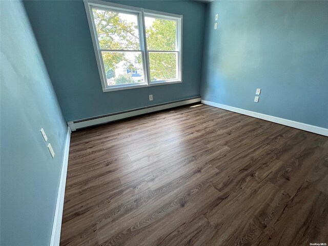 empty room with dark hardwood / wood-style floors and baseboard heating