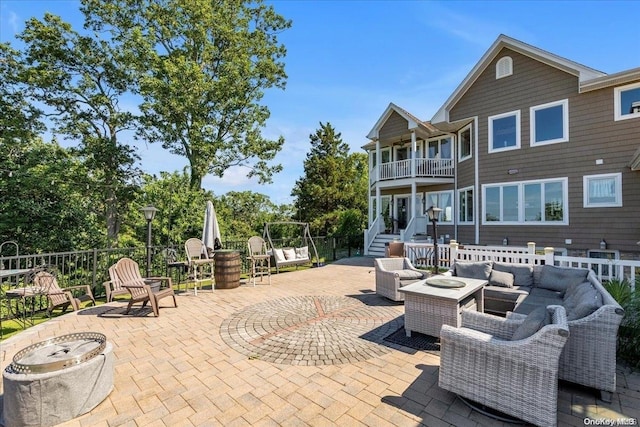 view of patio / terrace with a balcony and an outdoor living space with a fire pit