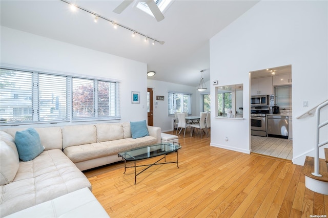 living room with plenty of natural light, light hardwood / wood-style floors, rail lighting, and ceiling fan