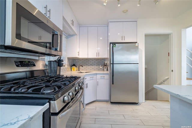 kitchen featuring backsplash, sink, light wood-type flooring, appliances with stainless steel finishes, and white cabinetry