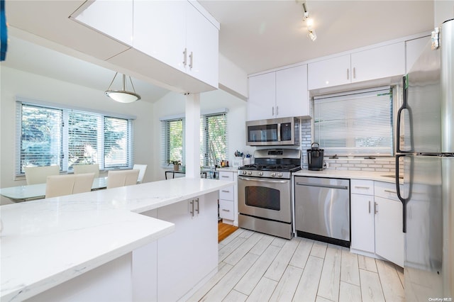 kitchen featuring light stone countertops, a wealth of natural light, stainless steel appliances, and decorative light fixtures