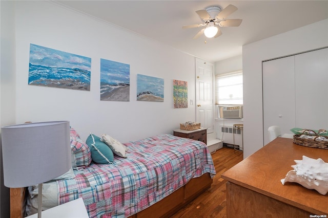 bedroom featuring dark hardwood / wood-style flooring, radiator, ceiling fan, cooling unit, and a closet