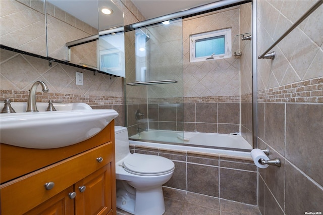 full bathroom with shower / bath combination with glass door, vanity, and tile walls