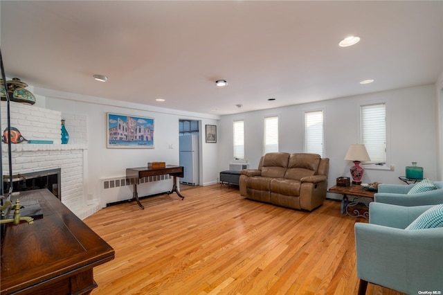 living room featuring radiator, light hardwood / wood-style flooring, and a fireplace