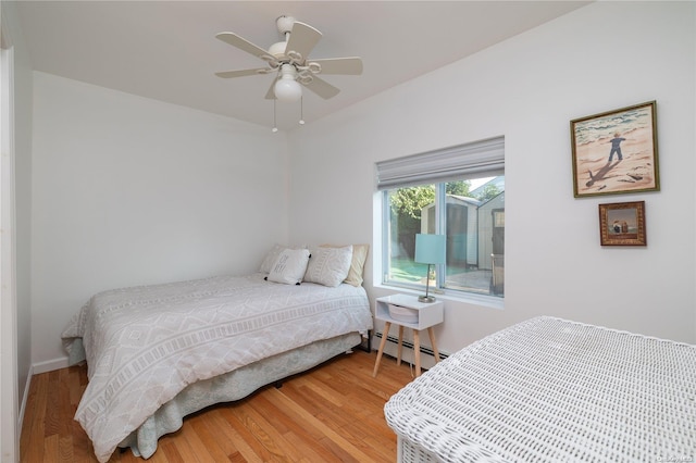 bedroom featuring hardwood / wood-style flooring, ceiling fan, and a baseboard heating unit