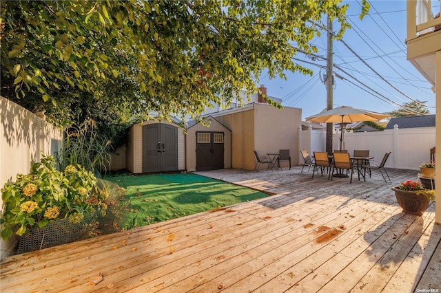 wooden terrace featuring a lawn and a shed