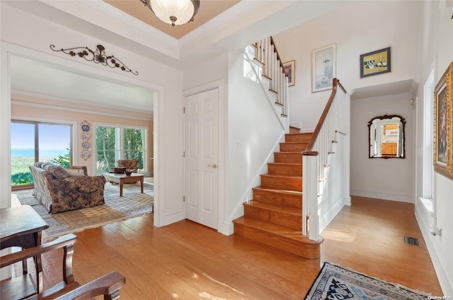 foyer entrance with light hardwood / wood-style floors and ornamental molding