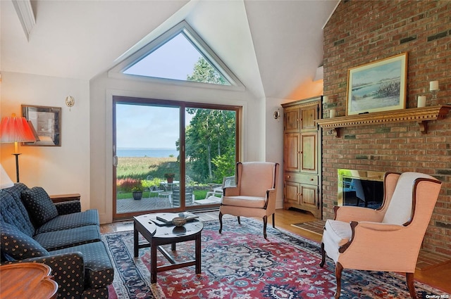 living room with a fireplace, high vaulted ceiling, brick wall, and hardwood / wood-style flooring