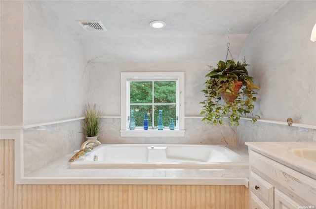 bathroom featuring a washtub, vanity, and vaulted ceiling