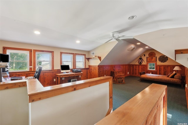 interior space featuring wooden walls, ceiling fan, vaulted ceiling, and dark colored carpet