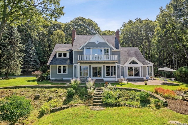 156 Ram Island Dr, Shelter Island, NY 11964 - rear view of house with a balcony, a lawn, a chimney, and a patio area