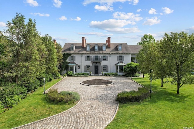 back of house featuring curved driveway, a lawn, and stucco siding