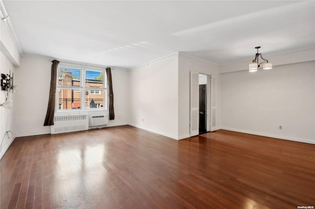 spare room featuring ornamental molding, an inviting chandelier, radiator, and dark wood-type flooring