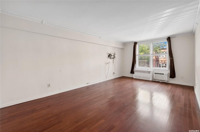 spare room featuring radiator, dark hardwood / wood-style flooring, a wall mounted air conditioner, and ornamental molding