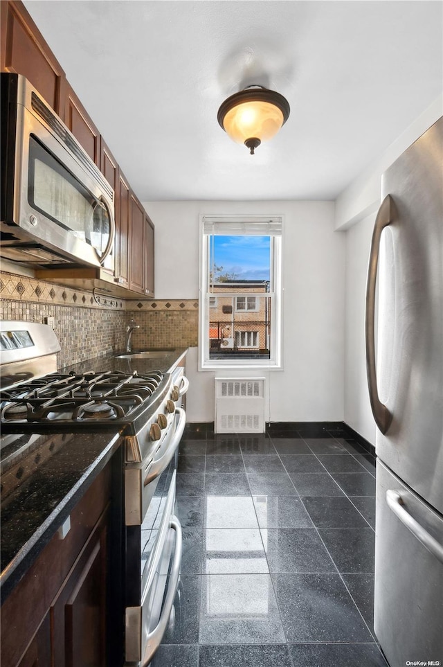 kitchen with radiator heating unit, backsplash, stainless steel appliances, and sink