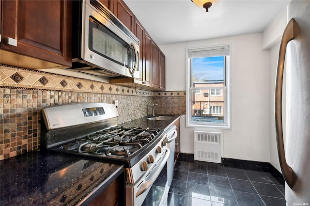 kitchen featuring radiator, sink, appliances with stainless steel finishes, and tasteful backsplash