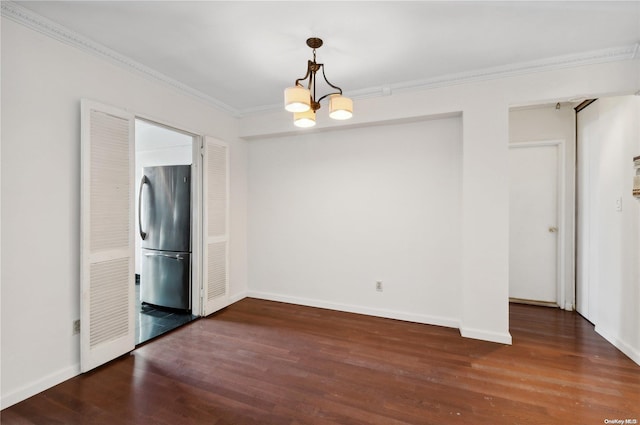 spare room with dark hardwood / wood-style flooring, an inviting chandelier, and ornamental molding