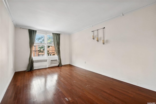 empty room with a wall unit AC, dark hardwood / wood-style flooring, crown molding, and radiator heating unit