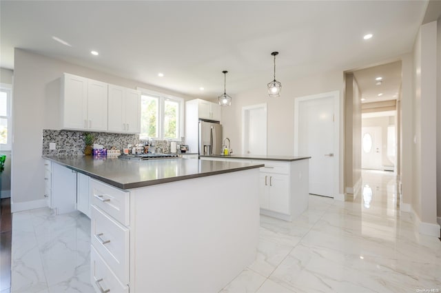 kitchen featuring stainless steel fridge, a center island, white cabinets, and hanging light fixtures