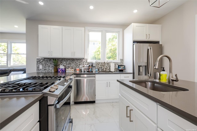 kitchen with white cabinets, sink, appliances with stainless steel finishes, and tasteful backsplash