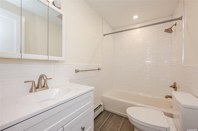 full bathroom featuring vanity, a baseboard heating unit, tile walls, toilet, and tiled shower / bath