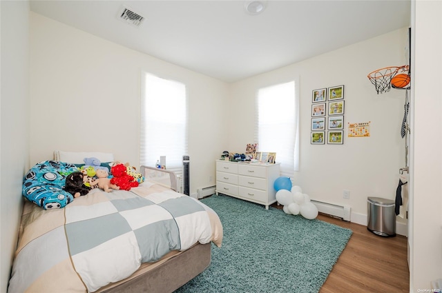 bedroom with wood-type flooring and a baseboard heating unit