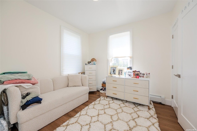 living area with wood-type flooring and a baseboard heating unit