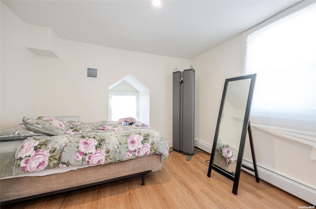 bedroom featuring a baseboard heating unit and light hardwood / wood-style flooring