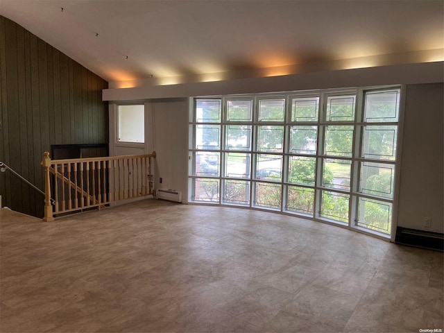 empty room with baseboard heating, a wealth of natural light, lofted ceiling, and wood walls