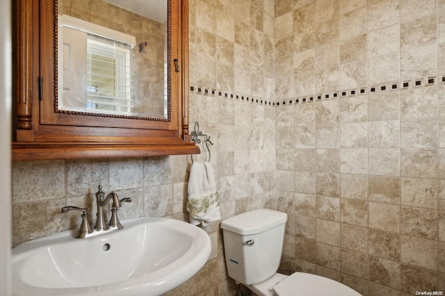 bathroom with sink, tile walls, and toilet