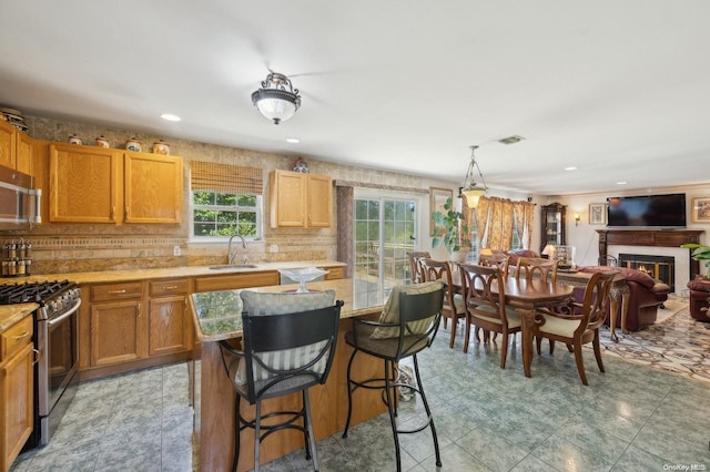 kitchen featuring sink, hanging light fixtures, stainless steel appliances, a kitchen breakfast bar, and decorative backsplash