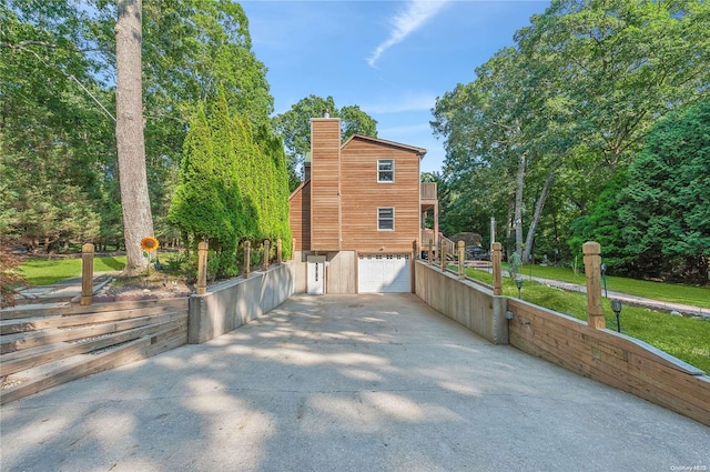 view of side of home featuring a garage and a balcony