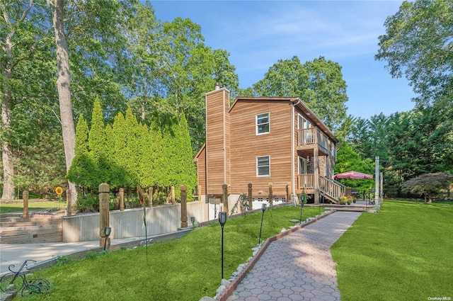 view of side of home with a balcony and a yard