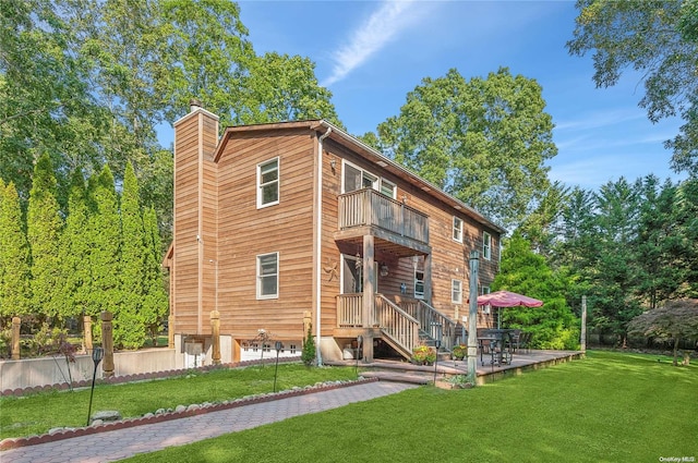 rear view of house with a lawn and a balcony