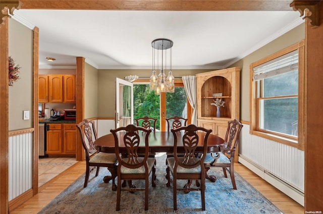 dining room featuring a chandelier, light wood-type flooring, baseboard heating, and crown molding