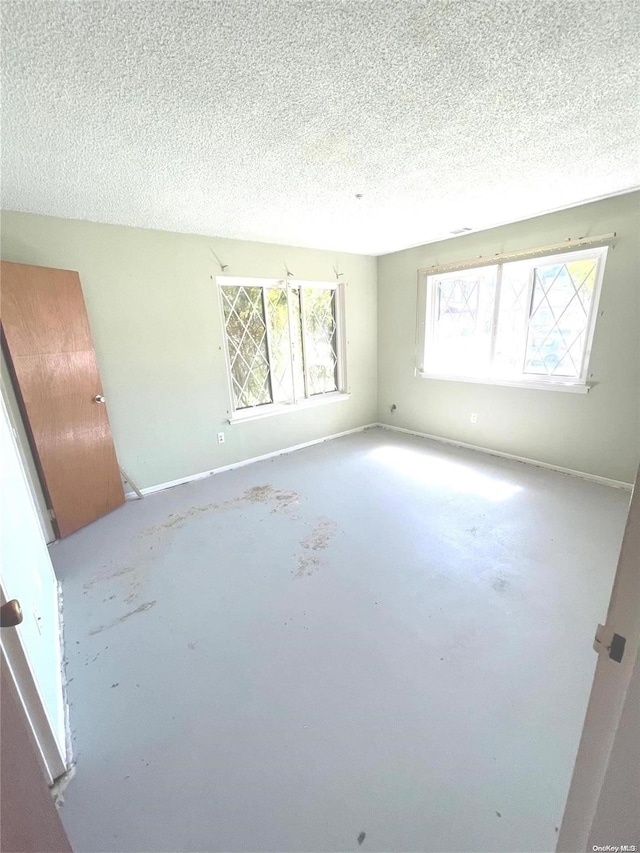 spare room featuring a textured ceiling, a wealth of natural light, and concrete floors